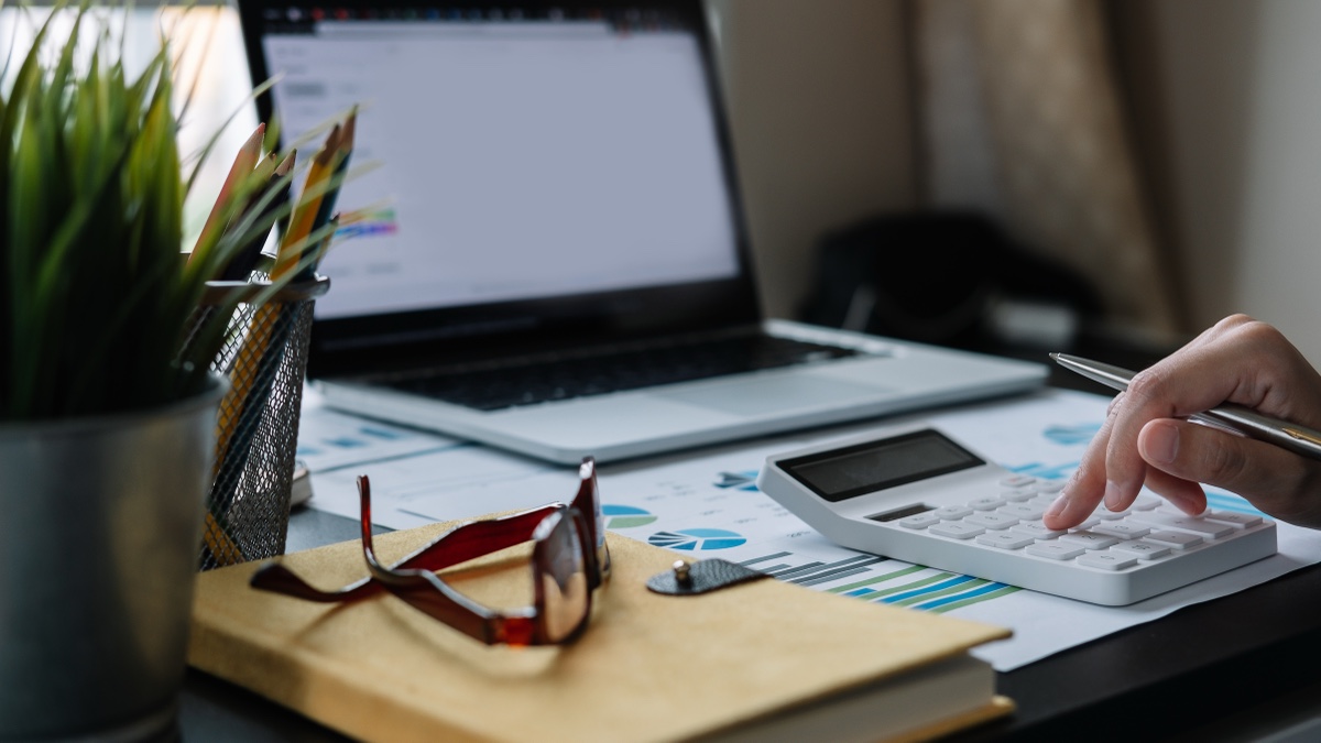 Accountant using a calculator and finance report, bookkeeper versus accountant