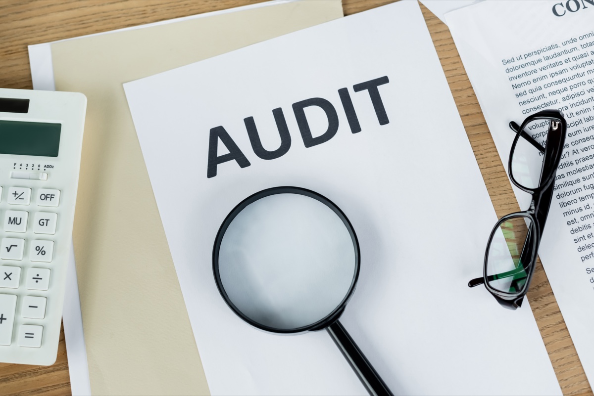 Magnifying glass over an audit document with a calculator, CRA audit preparation