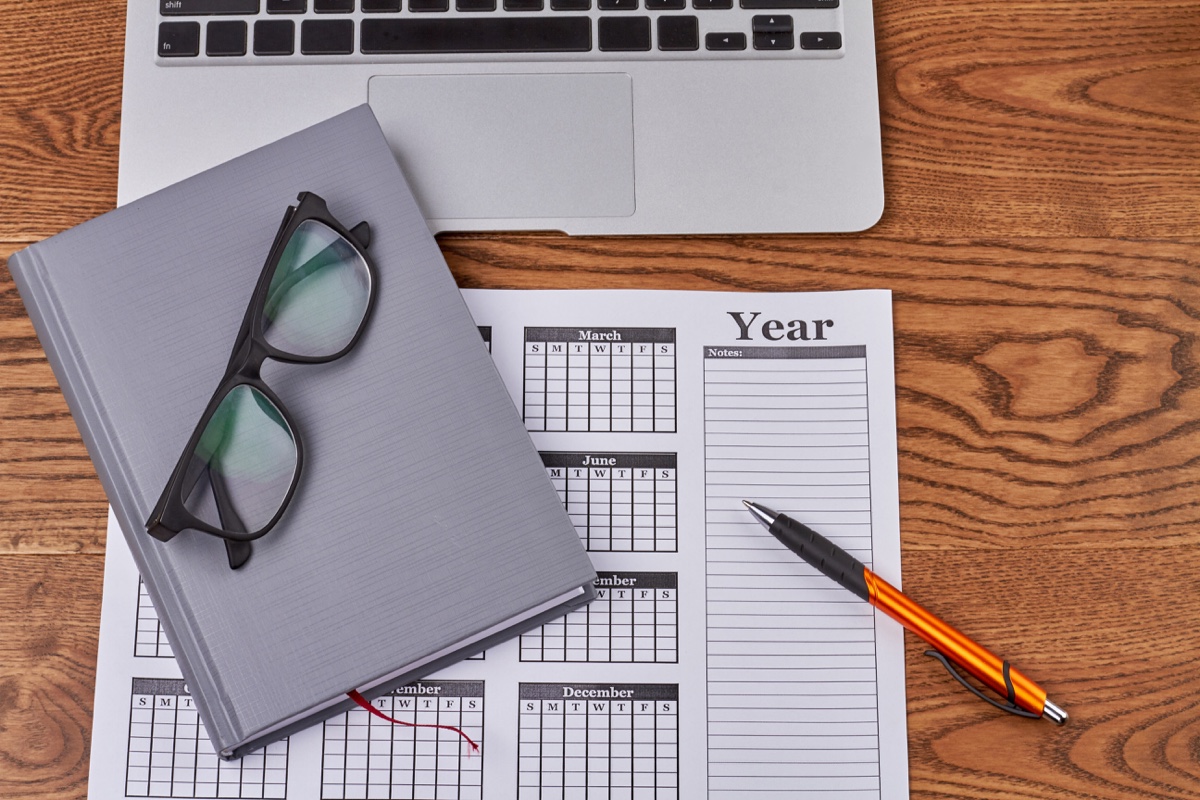 Year planner calendar, notepad and glasses on a desk for small-business year-end